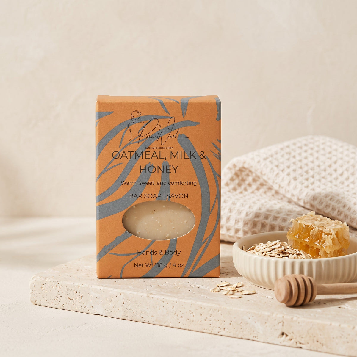 Pure Wash Oatmeal Milk & Honey soap bar in orange packaging with raw honeycomb and oats on a stone tray
