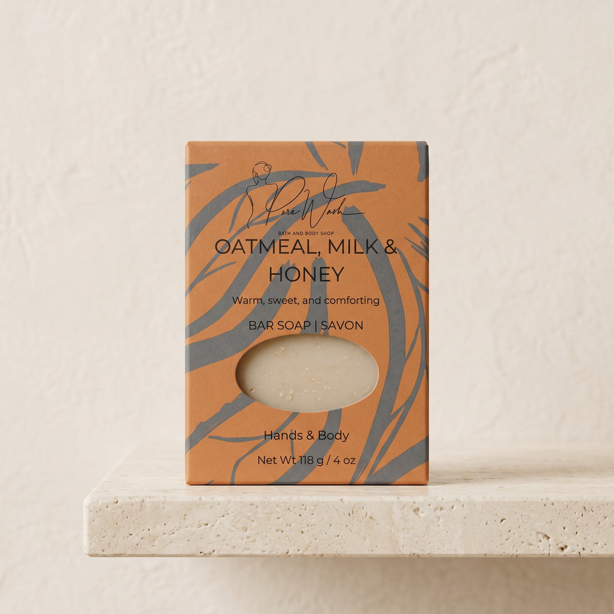 Pure Wash Oatmeal Milk & Honey soap bar in a tan box with grey leaf patterns, sitting on a textured stone shelf.