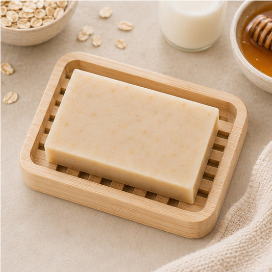 Pure Wash oatmeal milk and honey soap bar on a wooden dish with raw ingredients for dry skin