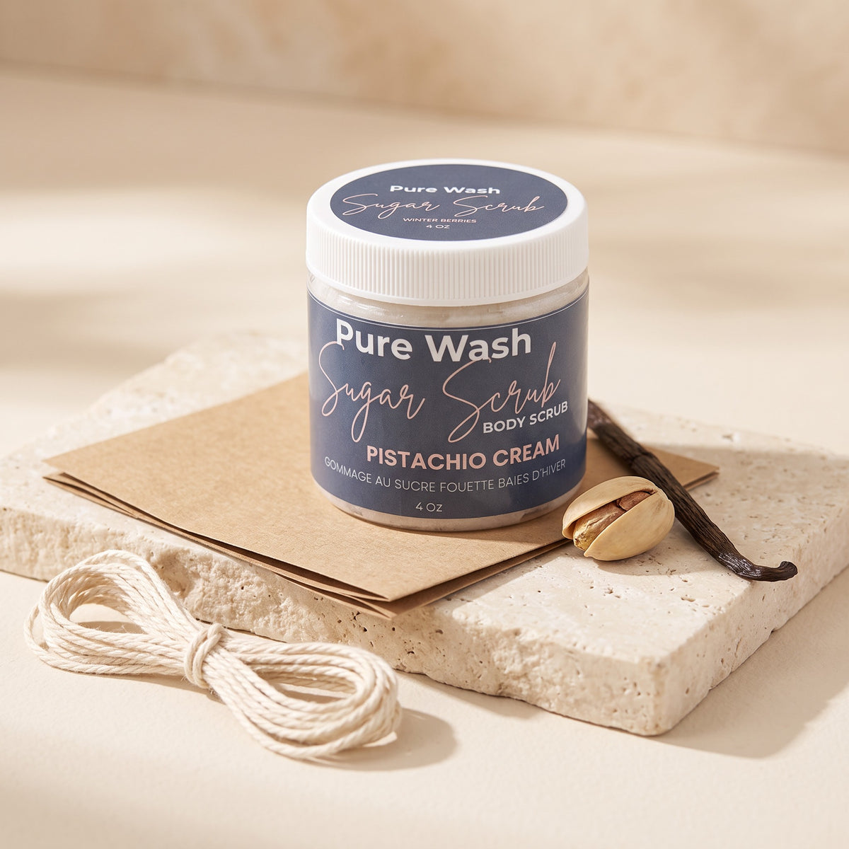 Pure Wash Pistachio Cream body sugar scrub in a jar on a stone tile with a pistachio nut and vanilla bean.