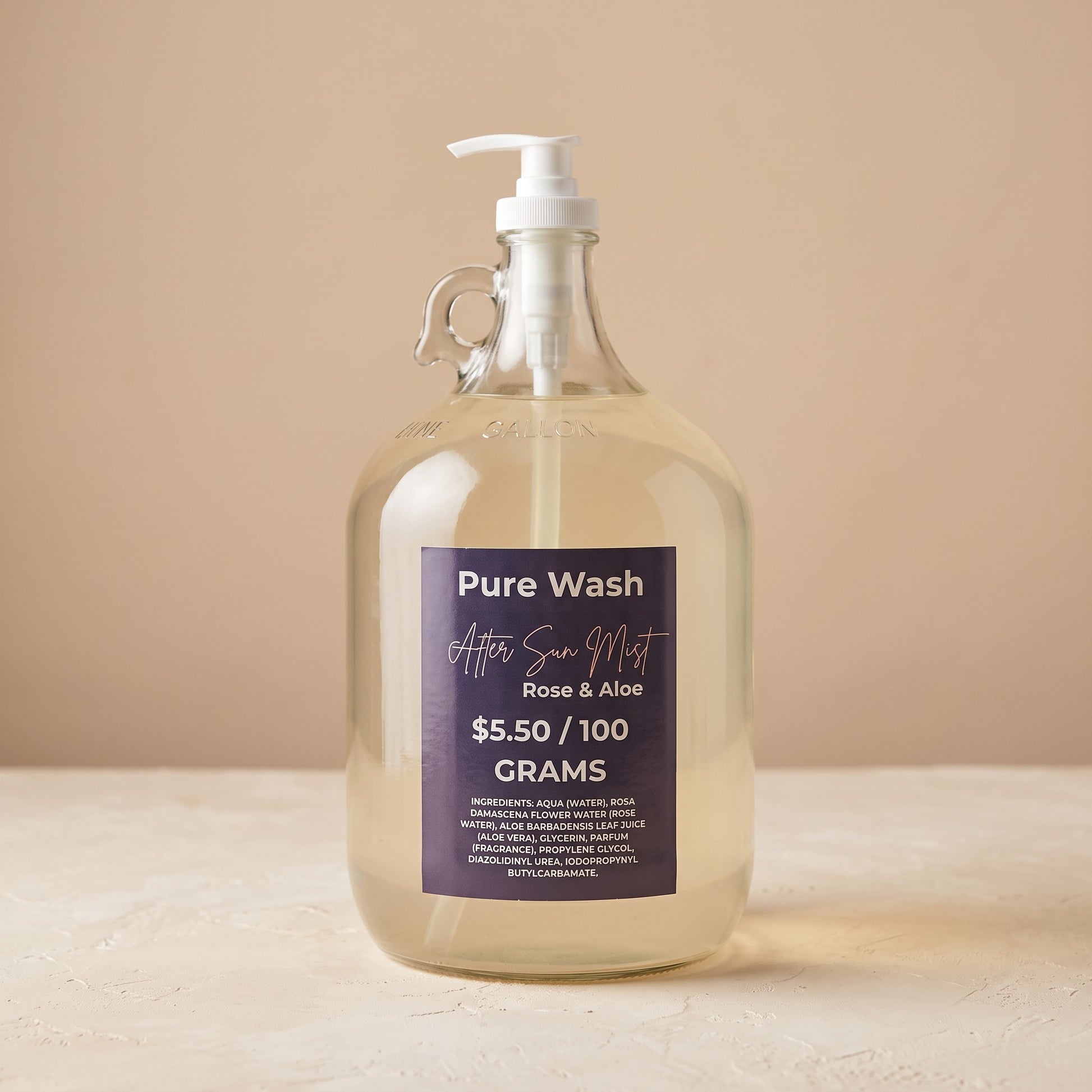 Pure Wash Rose & Aloe after-sun hydrating mist in a large glass refill jug with a white pump dispenser