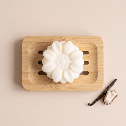 Pure Wash solid body lotion bar with shea butter and coconut oil on a wooden soap dish with vanilla and coconut