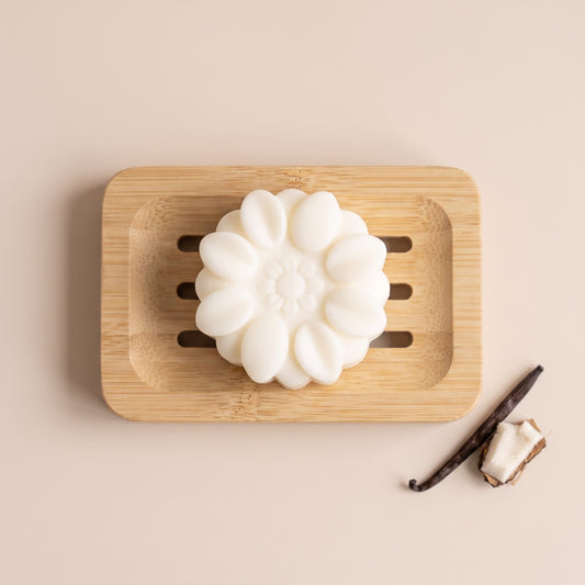 Pure Wash solid body lotion bar with shea butter and coconut oil on a wooden soap dish with vanilla and coconut