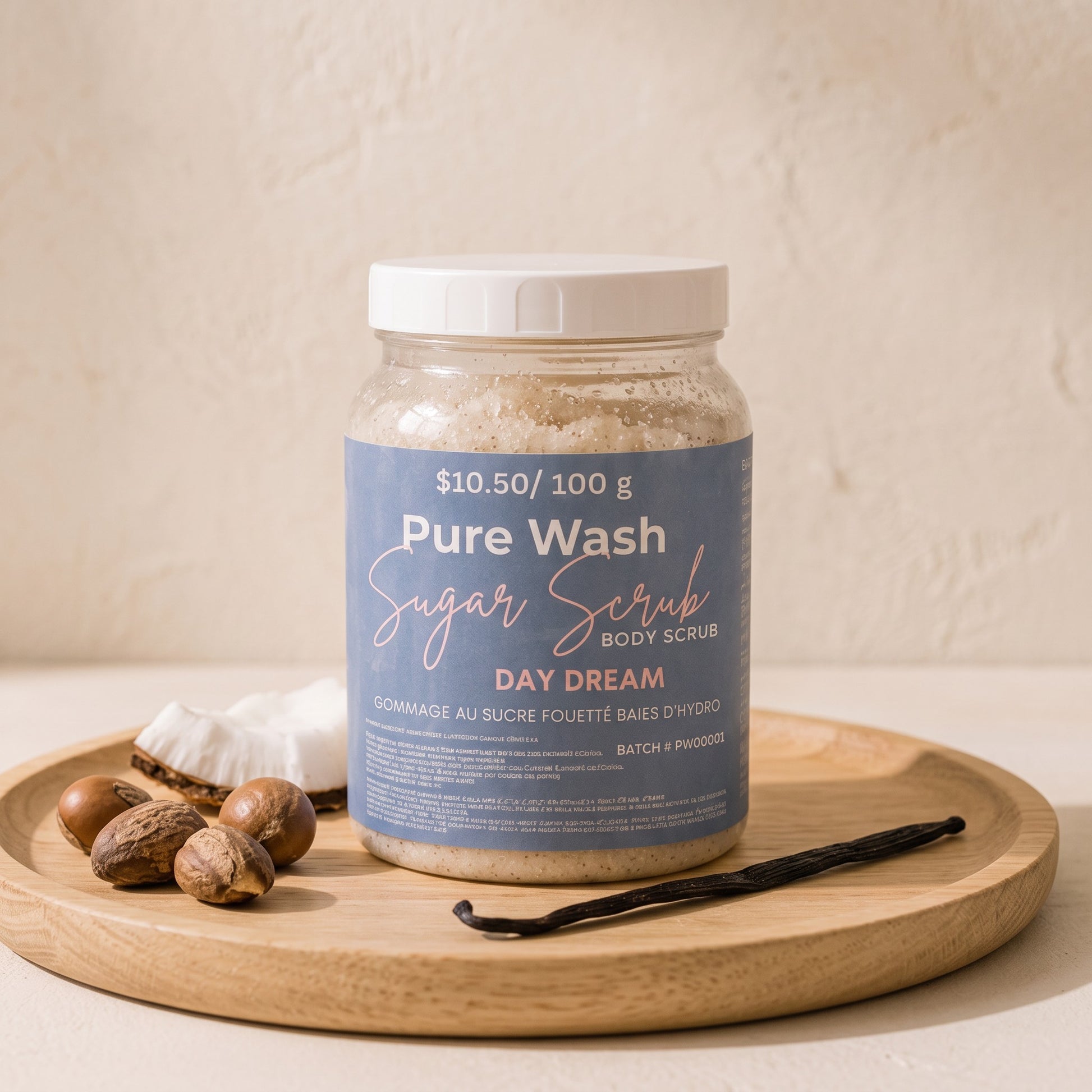 Pure Wash Day Dream sugar body scrub in a clear jar on a wooden tray with coconut pieces and a vanilla bean.