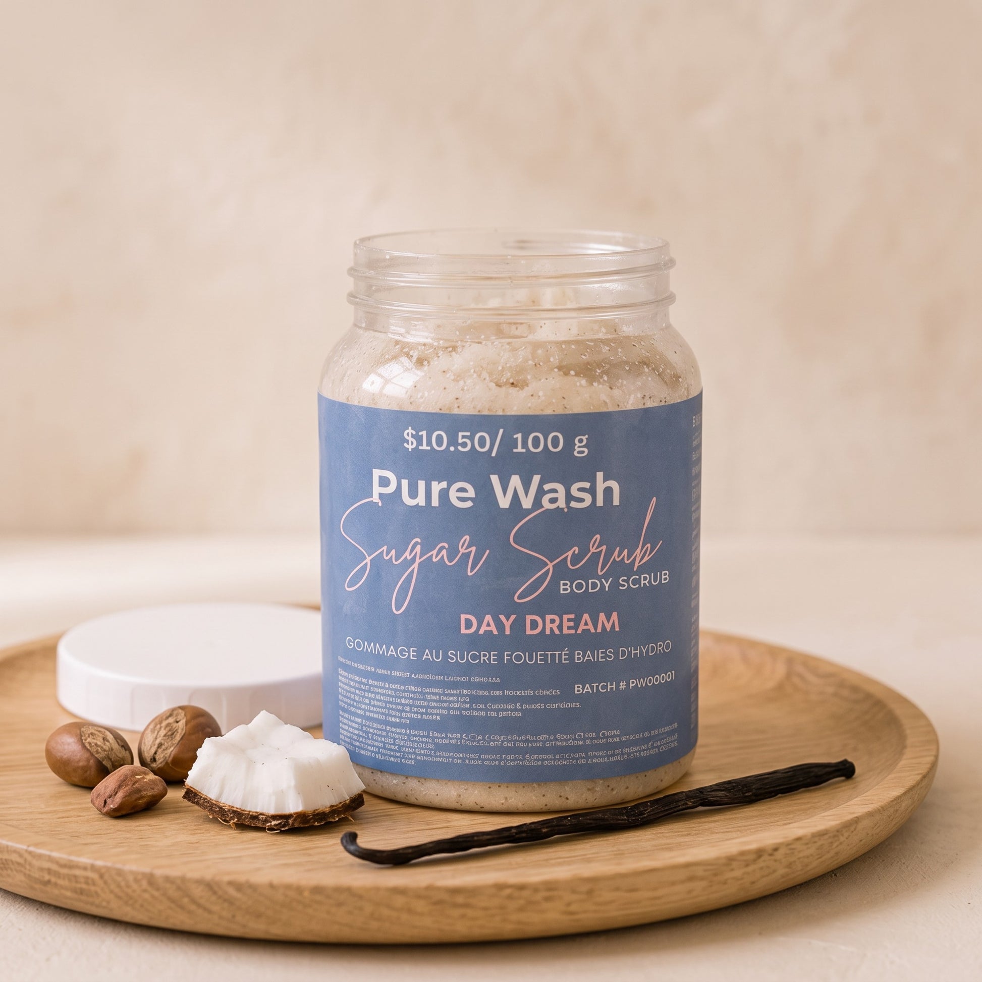 Pure Wash Day Dream sugar body scrub in a clear jar on a wooden tray with coconut, vanilla bean, and shea nuts.