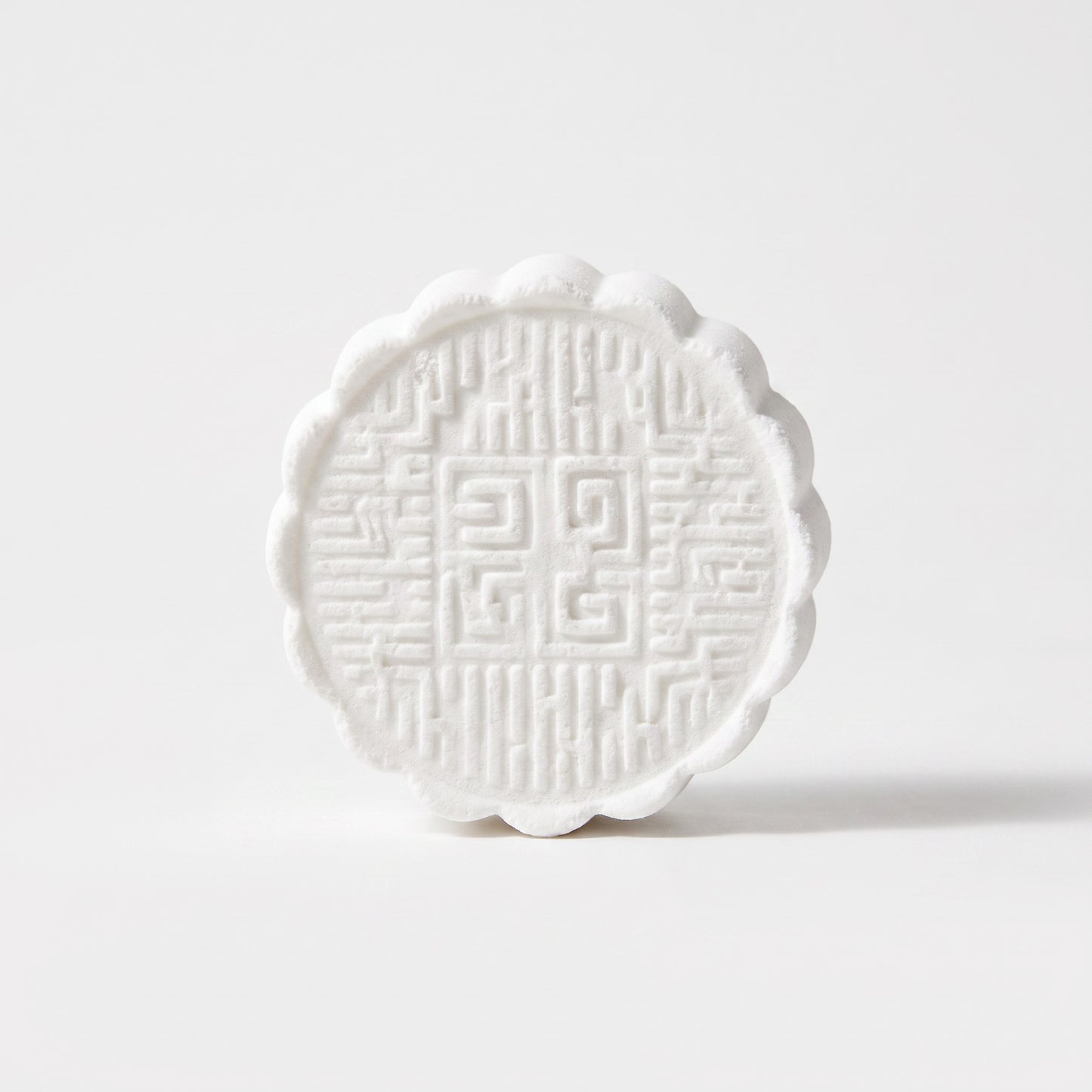 Pure Wash white circular shower steamer with intricate embossed geometric patterns and scalloped edges