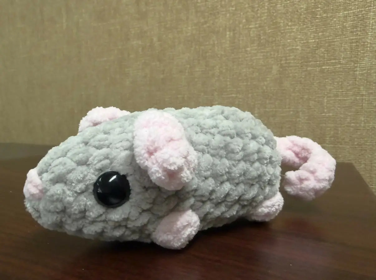 A soft light gray crocheted rat plush toy with pink ears and paws featuring shiny black bead eyes for decor or play