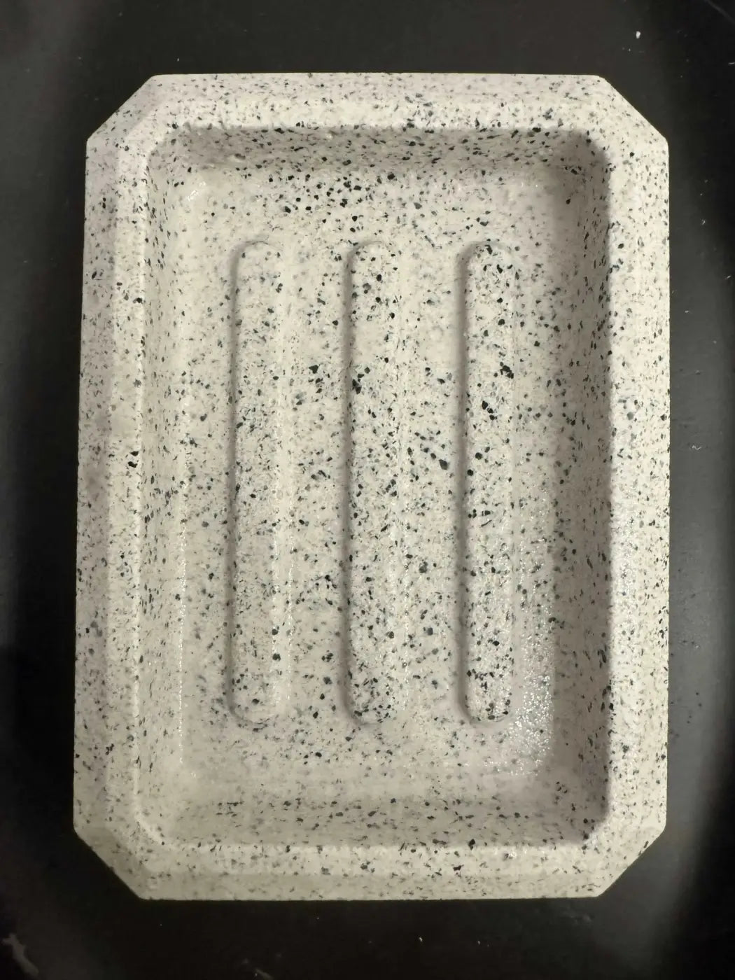 Rectangle soap dish in speckled gray stone with three raised grooves ideal for pure wash and penetrating sealer use