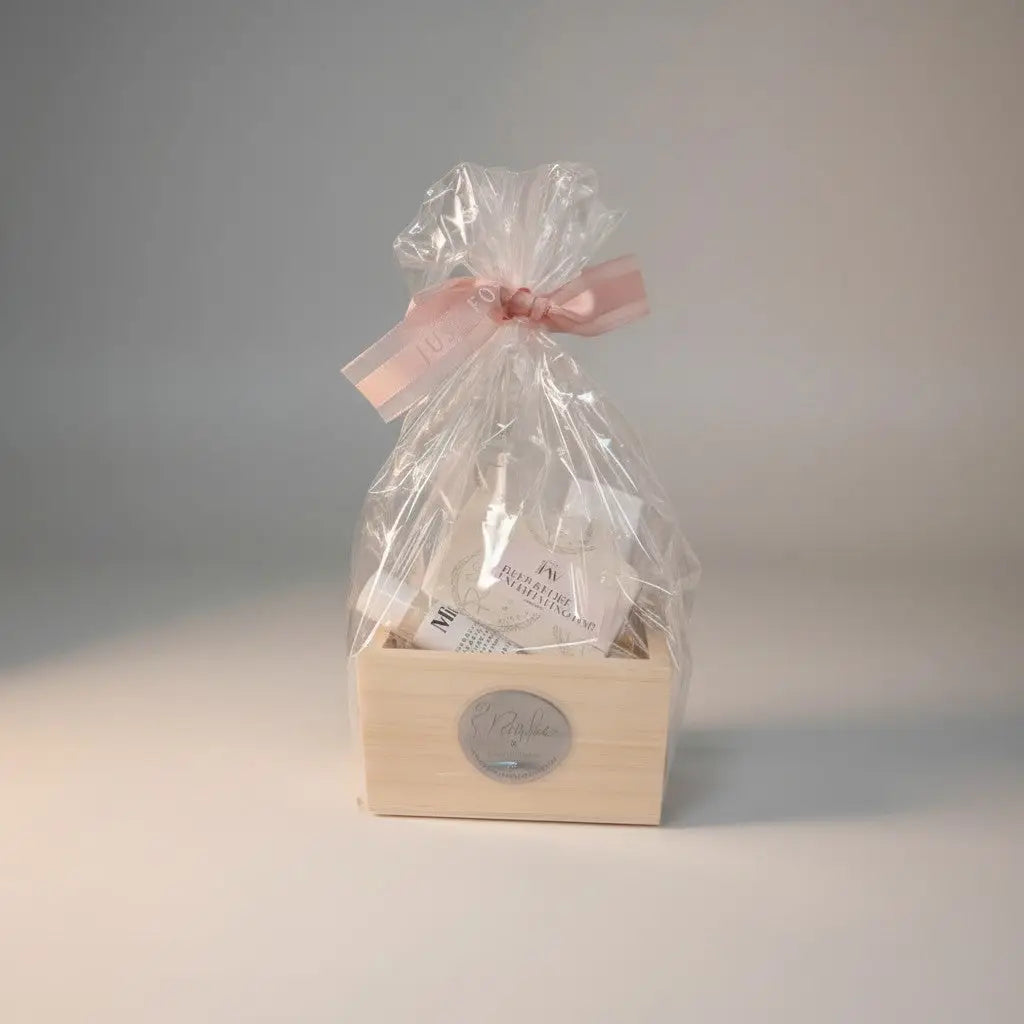 A light wood natural skincare gift box wrapped in cellophane with a soft pink ribbon for self-care set and exfoliation bar