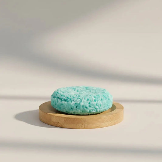 A round textured turquoise shampoo bar on a light wood stand ideal for pure wash for hair and hair softening tips