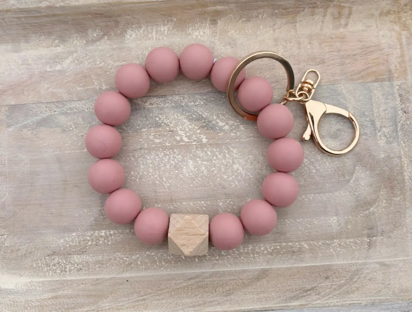 Pink silicone beaded wristlet with a wooden hexagon accent bead and gold tone metal clasp for stylish beaded wristlets