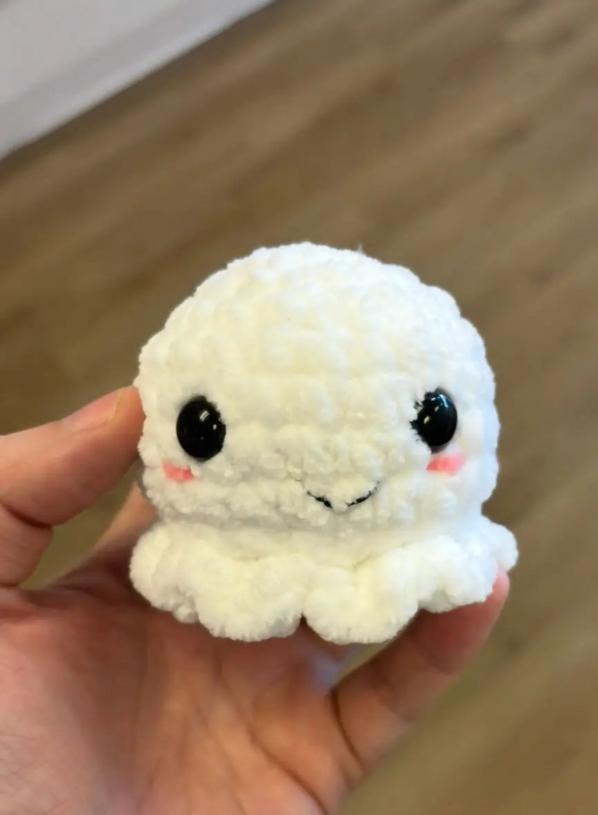 A small ghost soft white crocheted octopus with black bead eyes and pink blush cheeks for natural skincare canada
