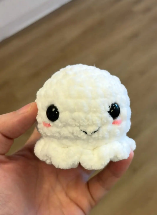 A small ghost soft white crocheted octopus with black bead eyes and pink blush cheeks for natural skincare canada