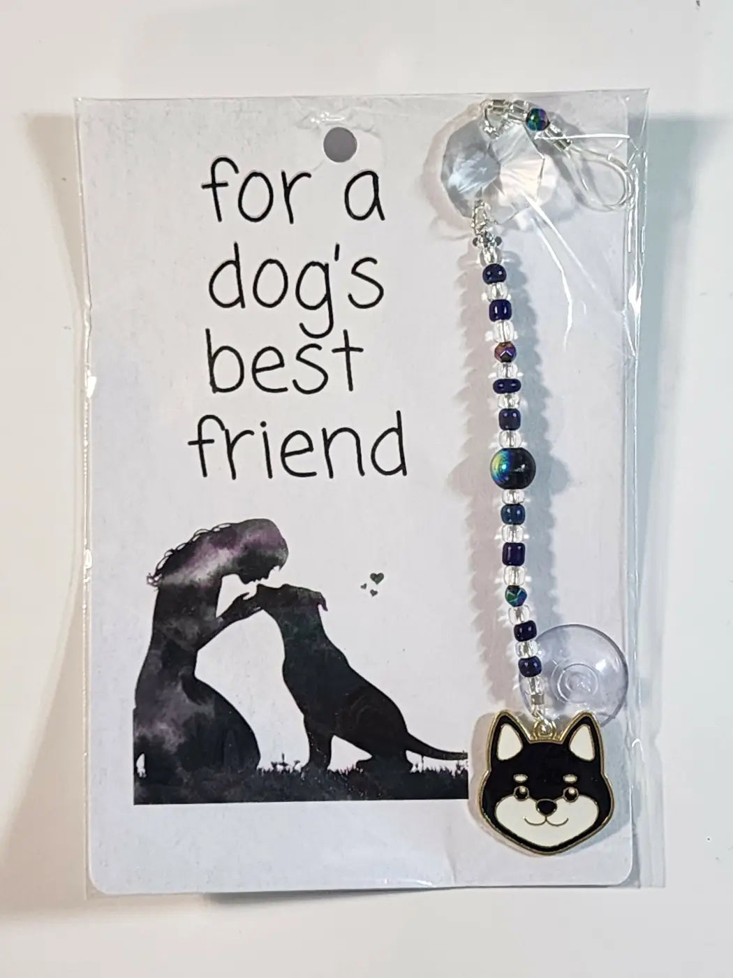 Small suncatcher featuring a black and white shiba inu face charm with dark blue iridescent beads and suction cup, ideal for canadian made skincare displays