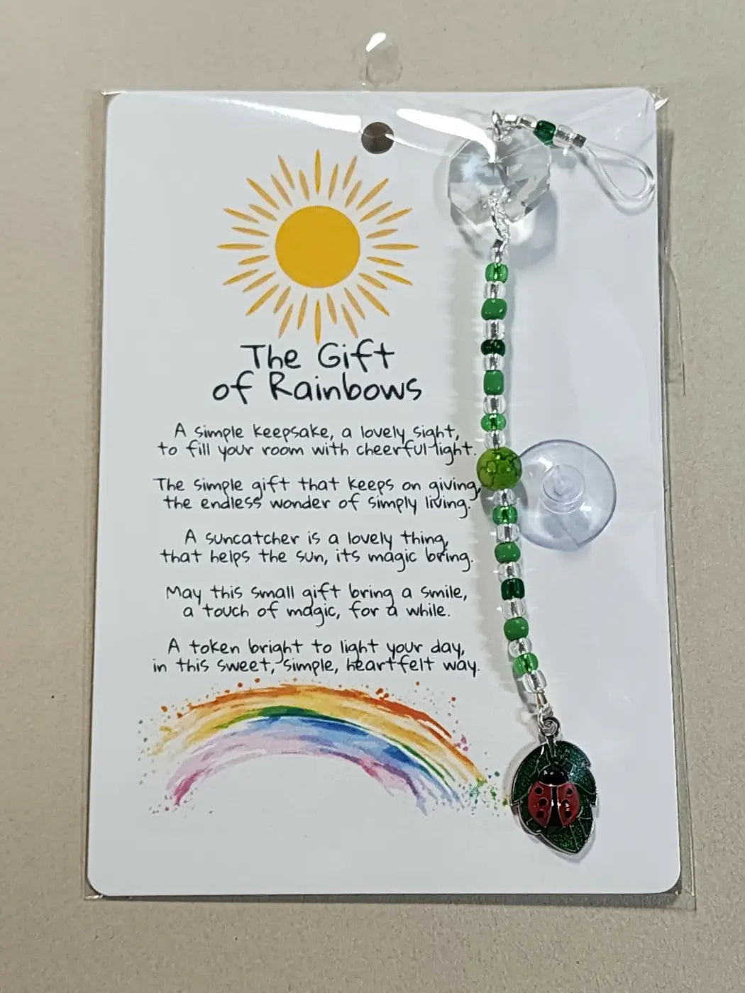 Small suncatcher with green beads red ladybug charm and clear crystal top reflecting canadian made skincare quality