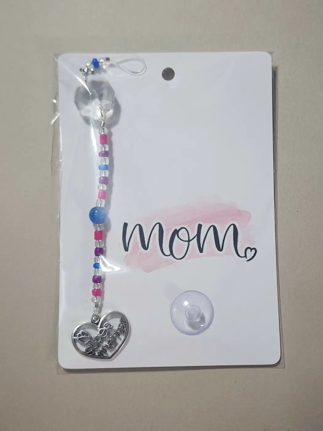 Small suncatcher with a silver heart-shaped charm engraved text hangs from a pink blue and purple beaded chain natural skincare canada