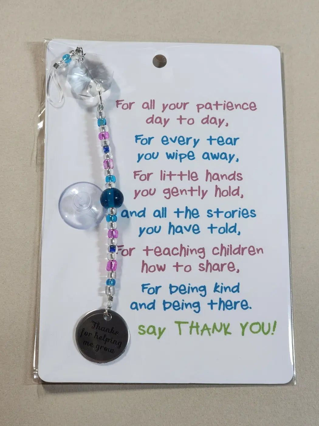 A small suncatcher car window cling with clear beads and a silver charm thanks for helping me grow canadian made skincare