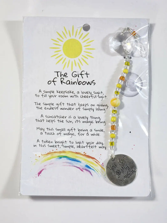 Small sunshine suncatcher with a silver-toned circular pendant and yellow amber beads hangs from a suction cup display