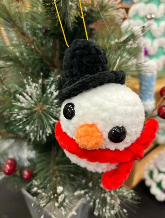 A plush crocheted snowman ornament with black top hat orange nose and red scarf perfect for natural skincare canada gifts