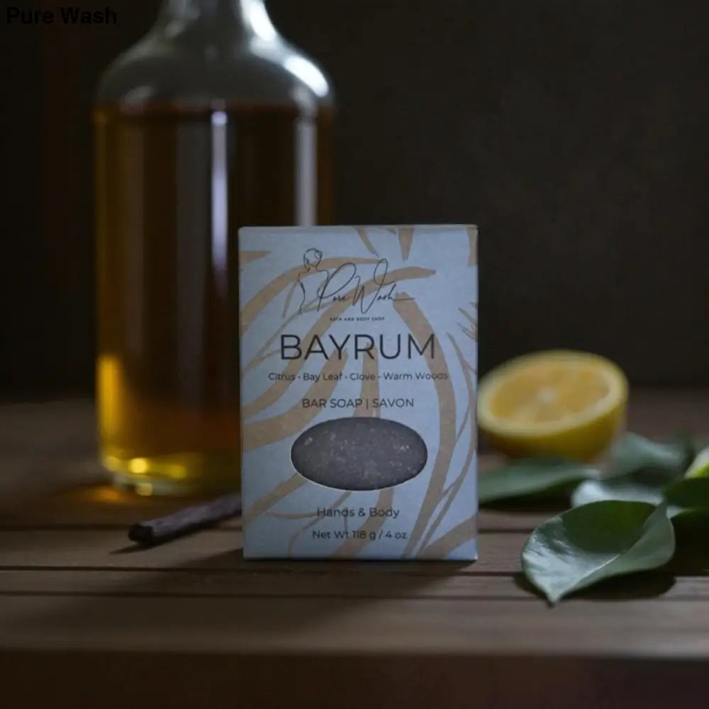 Bay rum bar soap packaging on a wooden surface with a bottle and lemon in the background