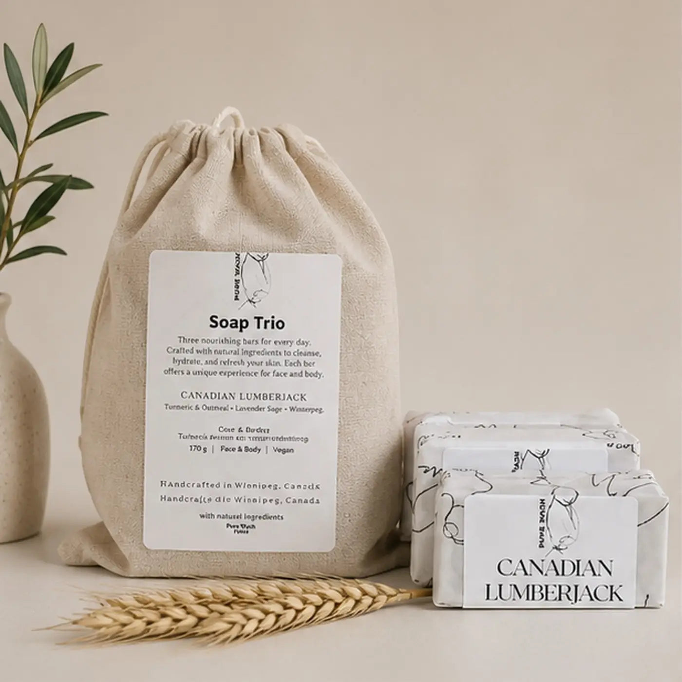 Beige linen canvas drawstring bag labeled soap trio containing three white botanical soap bars with canadian lumberjack design