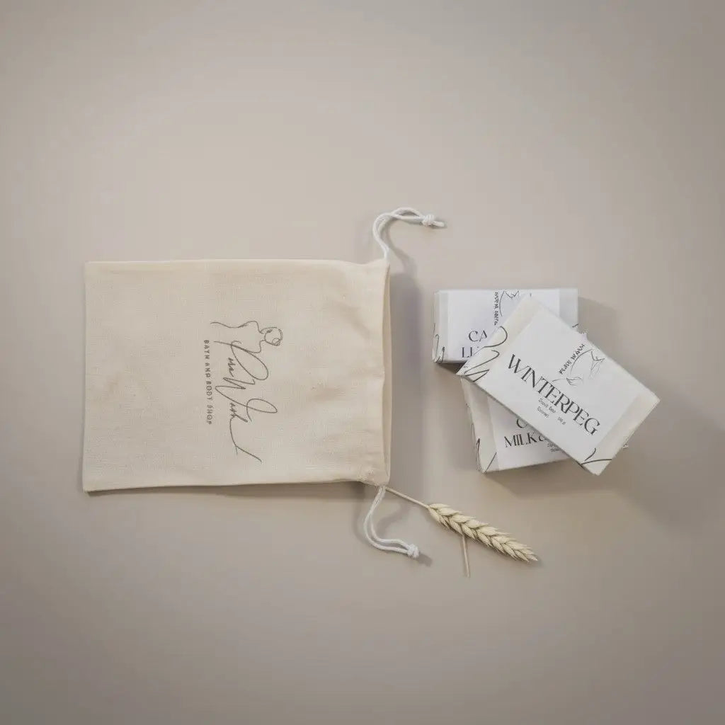 Cream-colored cotton canvas drawstring bag with black cursive script and embroidered detail for botanical soap bars
