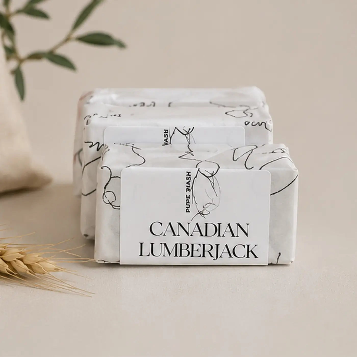 White rectangular botanical soap bar wrapped in minimalist packaging with canadian lumberjack label in cotton canvas drawstring bag
