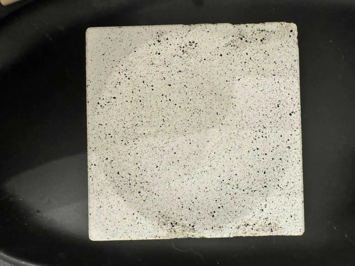 Square soap dish made of white concrete tile with black speckles suitable for use with penetrating sealer and pure wash