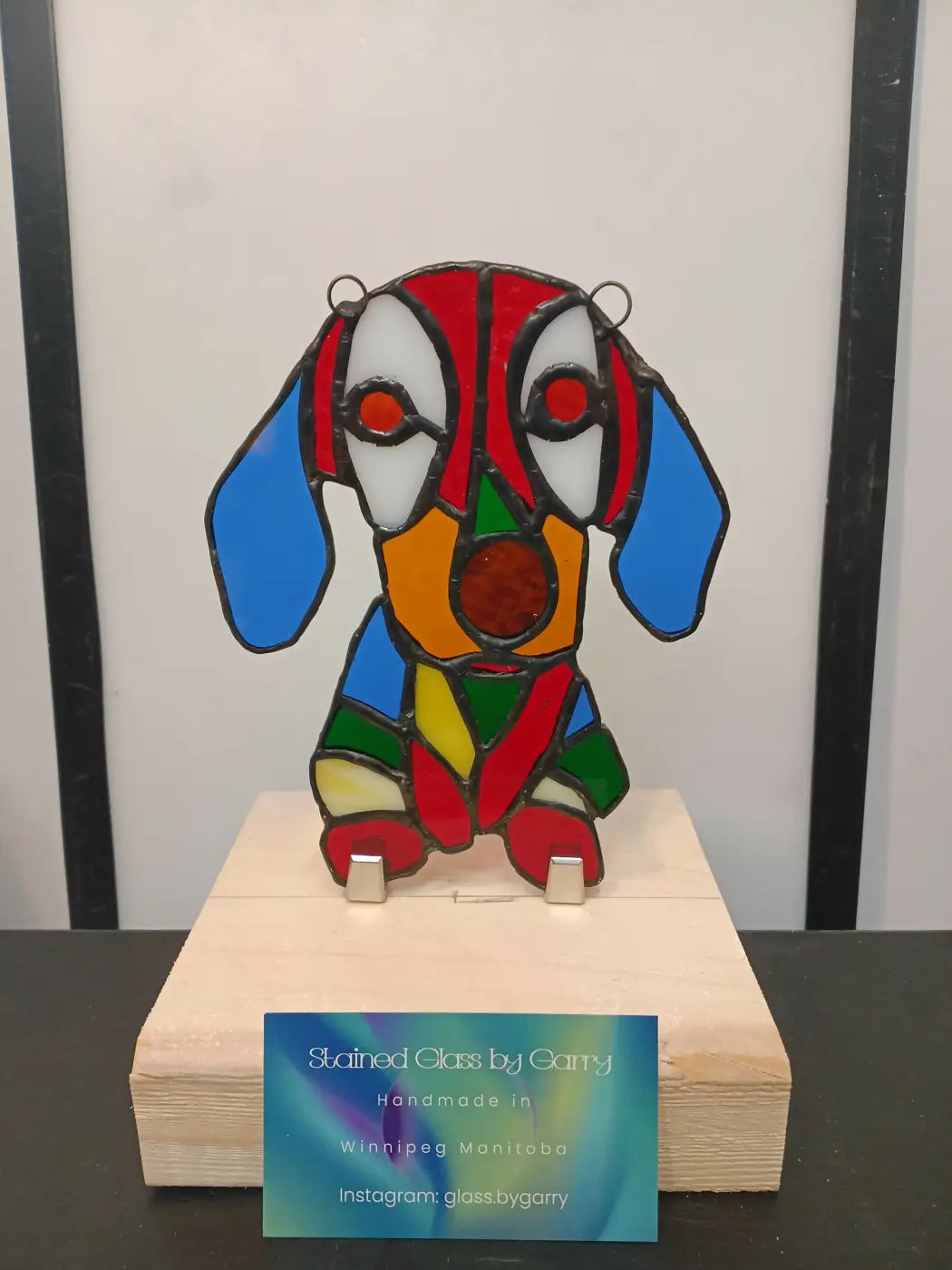 Colorful stained glass floppy-eared dog sculpture with red blue green and orange segments support local artisans