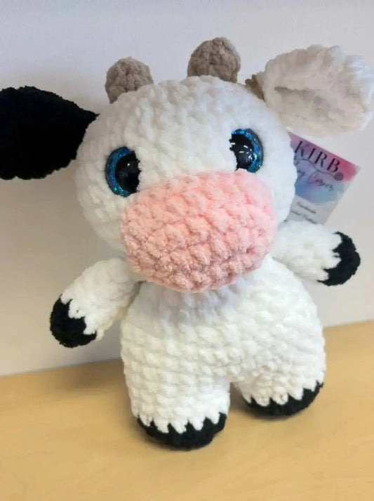Adorable handmade crocheted standing cow plush toy with white and black spots, blue glittery eyes, and pink nose for pure wash use