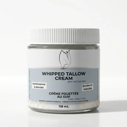 A sleek transparent glass jar with a white lid contains whipped tallow cream rich in essential fatty acids and avocado oil