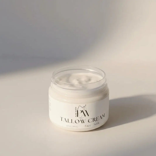 A clear glass jar of creamy white tallow cream with minimalist black text label featuring pure wash tallow and avocado oil