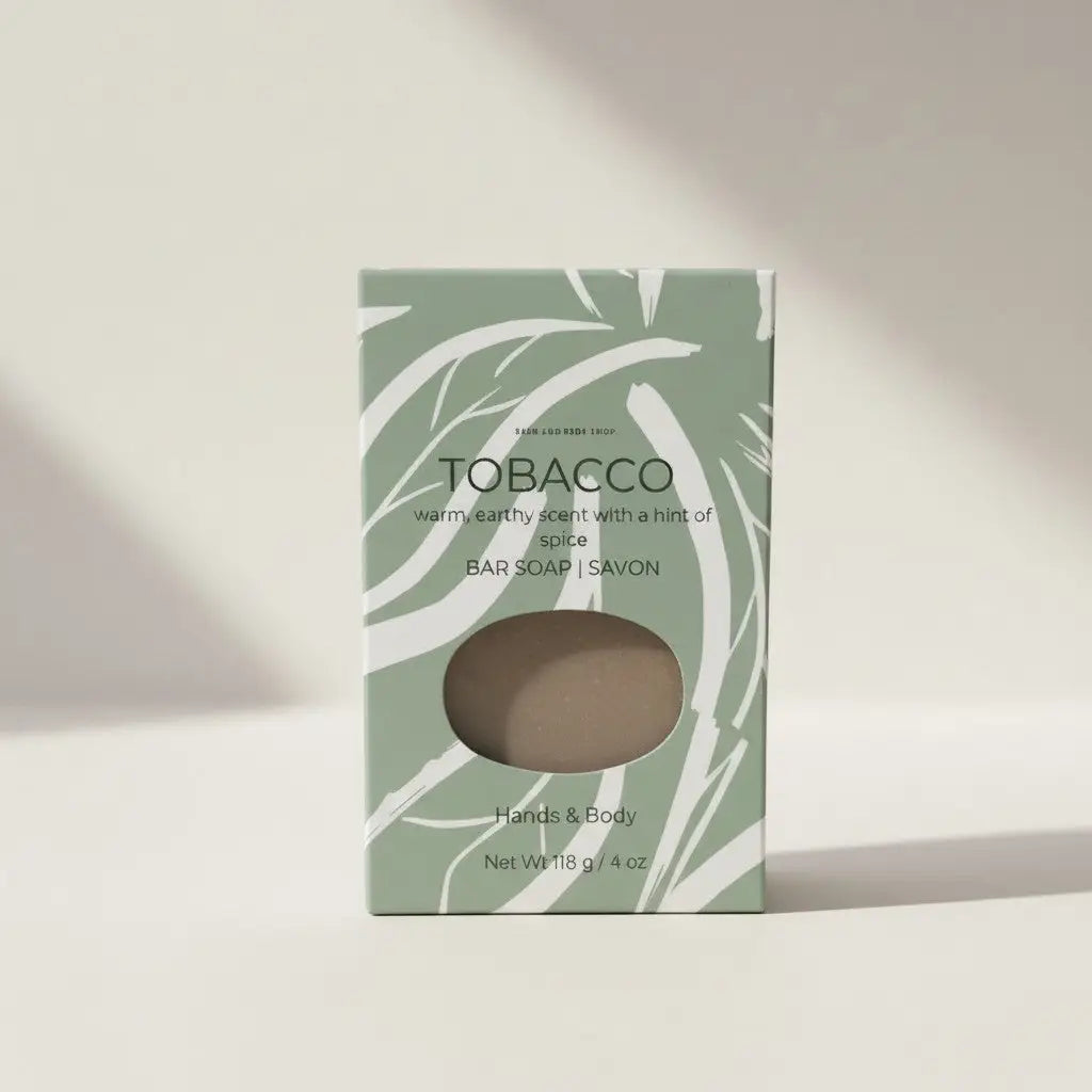 A rectangular mint green tobacco leaf soap box with white leaf patterns and a clear oval window showing the handcrafted palm oil bar