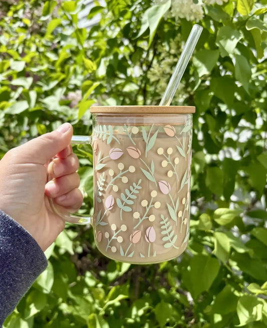 A tulip glass mug with bamboo lid and handle featuring pastel pink and green floral patterns and a glass straw