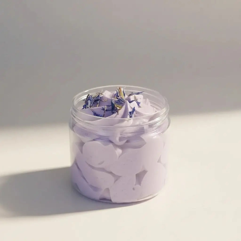 A clear glass jar of lavender whipped soap topped with dried blue flowers gentle cleanser for sensitive skin