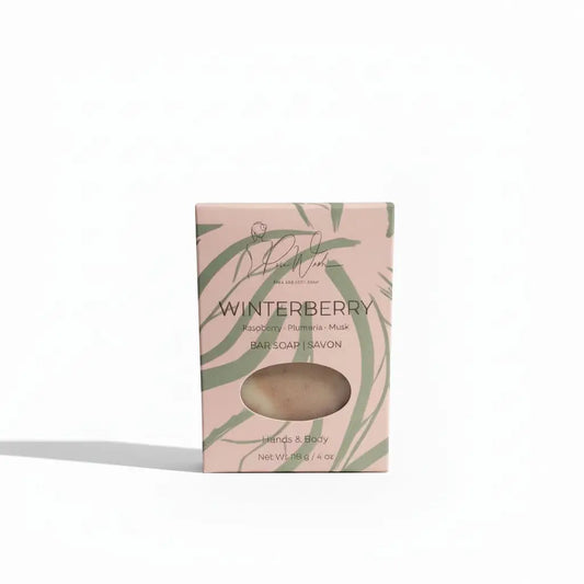 A pale pink winterberry soap bar box with green leafy patterns displaying a light beige handmade soap supporting healthy skin
