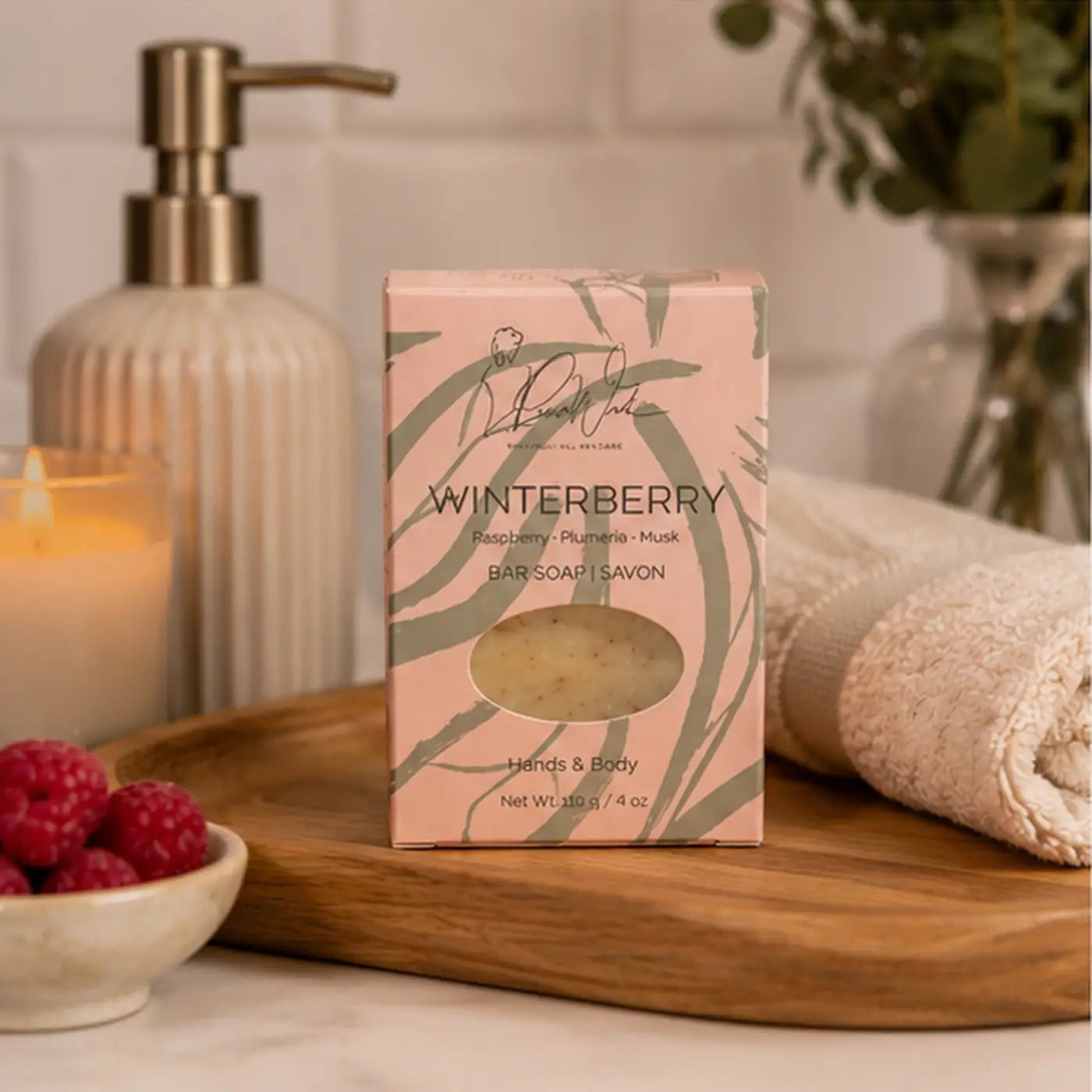 Pink rectangular box of winterberry soap bar with green leafy pattern and pale yellow handmade soap supporting healthy skin