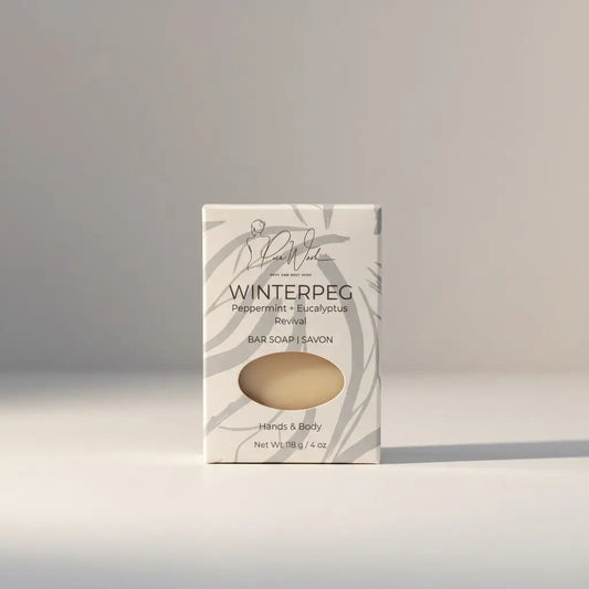 A creamy beige winterpeg soap inspired peppermint eucalyptus soap bar in a white box with gray leaf patterns by pure wren